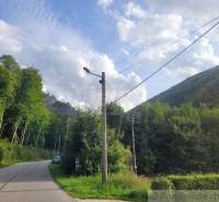 Stavebný pozemok pod lesom končiaci potôčikom v krásnom prírodnom pros - Cesta obklopená lesom, elektrické stĺpy, Beluša, Pozemky - bývanie.