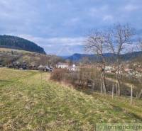 Stavebný pozemok s krásnym výhľadom nad obcou Jasenica pri Považskej B - Viditeľné Záhrady v Jasenici s domami a kopcovitou krajinou pod oblačnou oblohou.