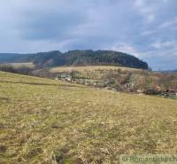 Stavebný pozemok s krásnym výhľadom nad obcou Jasenica pri Považskej B - Krajina v Jasenici s lúkami a lesnatým kopcom, dedinskými domami v pozadí.