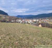 Stavebný pozemok s krásnym výhľadom nad obcou Jasenica pri Považskej B - Panoramatický výhľad na Záhrady v Jasenici s kopcami a oblohou v pozadí.