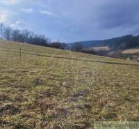 Stavebný pozemok s krásnym výhľadom nad obcou Jasenica pri Považskej B - Svahovité záhrady v Jasenici s výhľadom na okolité kopce a oblohu.