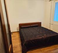 Prenájom pekný 3 izbový byt, Haburská ulica, Bratislava II. Ružinov - Spálňa v 3-izbovom byte s podlahou s dreveným dekorom a tmavým lôžkovinovým prehozom.