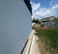 PREDAJ - Rodinný dom v obci Žíharec - Stena rodinného domu v Žihárci s priľahlým pozemkom pod modrou oblohou.