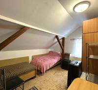 Na predaj dom vhodný na podnikanie sídlisko SNP v P. Bystrici! - Podkrovná izba v rodinnom dome s jednoduchým nábytkom a strešnými trámami.