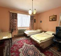 Na predaj dom vhodný na podnikanie sídlisko SNP v P. Bystrici! - Izba v rodinnom dome s kobercovou podlahou, dvomi posteľami a stolom.