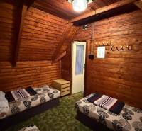 PRIPRAVUJEME Rekreačná chata - Zvolen - Kováčová na Predaj - Interiér chaty s dreveným obložením, posteľami a lustrom, útulné prostredie na relaxáciu.