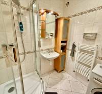 Na predaj – svetlý 2-izbový byt s loggiou a garážou | Bratislava - Kúpeľňa so sprchovým kútom v 2-izbovom byte, svetlé obklady, umývadlo, práčka.