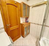 Na predaj – svetlý 2-izbový byt s loggiou a garážou | Bratislava - Kúpeľňa v 2-izbovom byte s práčkou, drevenými skrinkami a sprchovým kútom.