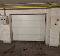 Na predaj – svetlý 2-izbový byt s loggiou a garážou | Bratislava - Uzavretá garážová brána v podzemnom parkovisku so stenou a elektrickou skrinkou.