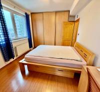 Na predaj – svetlý 2-izbový byt s loggiou a garážou | Bratislava - Spálňa s posteľou, vstavanou skriňou a podlahou s dreveným dekorom v 2-izbovom byte.