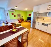 Na predaj – svetlý 2-izbový byt s loggiou a garážou | Bratislava - Otvorená kuchyňa s obývačkou a podlahou s dreveným dekorom v 2-izbovom byte.