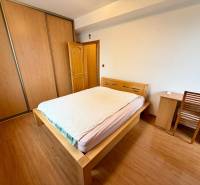 Na predaj – svetlý 2-izbový byt s loggiou a garážou | Bratislava - Spálňa v 2-izbovom byte so skriňou, posteľou a podlahou s dreveným dekorom.