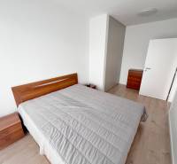 Na prenájom kompletne zariadený 2i byt s parkingom, Nový Ružinov - Spálňa v 2-izbovom byte s podlahou s dreveným dekorom, svetlé steny, drevený nábytok.
