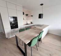 Na prenájom kompletne zariadený 2i byt s parkingom, Nový Ružinov - Kuchyňa v 2-izbovom byte s kuchynským ostrovčekom, dreveným dekorom a zelenými stoličkami.