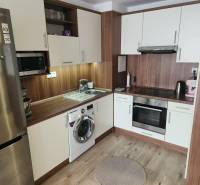 Na prenájom  1,5 izbový byt  Učňovská ulica Šaca - Kuchyňa v 2-izbovom byte s podlahou s dreveným dekorom, sporákom a chladničkou.