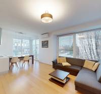 RADO I 4-izbový byt 97 m2 + loggia I Ivanka pri Dunaji  - Obývacia izba s rohovou sedačkou, jedálenským stolom a podlahou s dreveným dekorom v 4-izbovom byte.