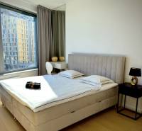 Prenájom 3-izbový byt s loggiou, SKY PARK, Bratislava - Spálňa v 3-izbovom byte s posteľou, nočným stolíkom a podlahou s dreveným dekorom.