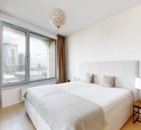 Prenájom 3-izbový byt s terasou, SKY PARK, Bratislava - Spálňa v 3-izbovom byte s veľkým oknom, závesmi a podlahou s dreveným dekorom.