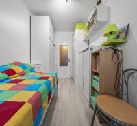 Ponúkame na predaj 3-izb.byt Vígľašská ul., Bratislava - Petržalka. - Úzka izba v 3-izbovom byte s farebnou prikrývkou a podlahou s dreveným dekorom.