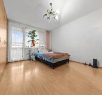 Ponúkame na predaj 3-izb.byt Vígľašská ul., Bratislava - Petržalka. - Spálňa v 3-izbovom byte s podlahou s dreveným dekorom, posteľou a veľkým oknom.