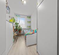 Ponúkame na predaj 3-izb.byt Vígľašská ul., Bratislava - Petržalka. - Izba v 3-izbovom byte s farebnými závesmi, posteľou a rastlinami, podlaha s dreveným dekorom.