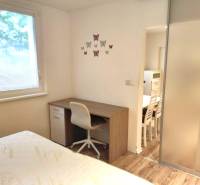 2-izbový byt, 49 m2, Cabanova ul., Bratislava - Dúbravka - Izba v 2-izbovom byte na ulici Cabanova, písací stolík, stolička, nástenné dekorácie.