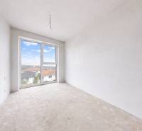 3i. BYT S VLASTNÝM TEP. ČERPADLOM + KLIMATIZÁCIA A EXTERIÉROVÉ ŽALÚZIE - Nezariadená izba v 3-izbovom byte s veľkým oknom a výhľadom na strechy.