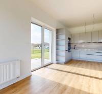 3i. BYT S VLASTNÝM TEP. ČERPADLOM + KLIMATIZÁCIA A EXTERIÉROVÉ ŽALÚZIE - Kuchyňa a obývacia časť v 3-izbovom byte s veľkými oknami a výhľadom na zeleň.