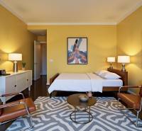 Predaj 3 izbový byt, 86 m2, Francisciho ul, Staré mesto, BAI . - Žlté steny, posteľ, kreslá a rastlina v 3-izbovom byte s podlahou s dreveným dekorom.