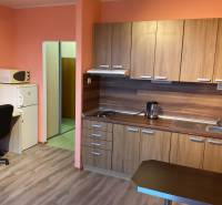 I prenájom Útulne zariadená garsónka s loggiou – Petržalka - Garsónka s kuchynskou linkou, stolom, stoličkou a podlahou s dreveným dekorom.