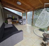 Útulný rodinný dom v tichej obci Hont, Maďarsko - Terasa v rodinnom dome v Honte s hojdačkou, pohovkou a prúteným kreslom.