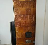 Útulný rodinný dom v tichej obci Hont, Maďarsko - Kachľová pec v rodinnom dome s podlahou s dreveným dekorom.