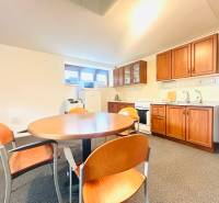 PRENÁJOM- KANCELÁRSKÝ PRIESTOR -120m2- KOMÁROVSKÁ - Kuchyňa v rodinnom dome s jedálenským stolom, stoličkami a kuchynskou linkou s dreveným dekorom.