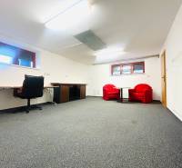 PRENÁJOM- KANCELÁRSKÝ PRIESTOR -120m2- KOMÁROVSKÁ - Kancelária v rodinnom dome má koberec, pracovný stôl a červené kreslá.