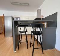 Prenájom 2 izbový 78 m2 + 30 m2 terasa,novostavba Koliba,zariadený - Kuchyňa 2-izbového bytu s barovým pultom, stoličkami a podlahou s dreveným dekorom.