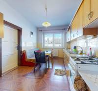 Rodinný dom Zvolen - Lieskovec - Kuchyňa s podlahou s dreveným dekorom, svetlým nábytkom a jedálenským stolom v rodinnom dome.