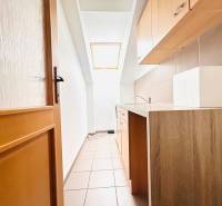 KANCELÁRSKE PRIESTORY- 120m2- KOMÁROVSKÁ - Úzka kuchynská časť v kancelárii s oknom a podlahou s dreveným dekorom.