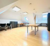 KANCELÁRSKE PRIESTORY- 120m2- KOMÁROVSKÁ - Podkrovné kancelárie s podlahou s dreveným dekorom, strešnými oknami a kancelárskym zariadením.