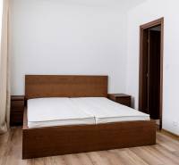 PRENÁJOM 3 izbový luxusný byt  v centre Nitry s veľkou terasou - Spálňa v 3-izbovom byte s posteľou z tmavého dreva a podlahou s dreveným dekorom.