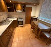 2 izbový byt s balkónom Topoľčany  - Kuchyňa 3-izbového bytu s dreveným dekorom skriniek a jedálenským sedením.