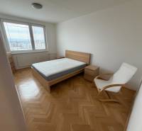 2 izbový byt s balkónom Topoľčany  - Spálňa s posteľou, kreslom a výhľadom. Podlaha s dreveným dekorom v 3-izbovom byte.