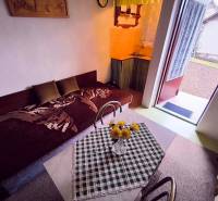 ‼️BRODZANY - ZÁHRADA S MUROVANOU CHATKOU NA PREDAJ, okr. PARTIZÁNSKE‼️ - Interiér chaty s pohovkou, jedálenským stolom a otvorenými dverami do záhrady.