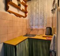 ‼️BRODZANY - ZÁHRADA S MUROVANOU CHATKOU NA PREDAJ, okr. PARTIZÁNSKE‼️ - Kuchynka v chate s dreveným dekorom, poličkou a závesom pri okne.