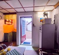 ‼️BRODZANY - ZÁHRADA S MUROVANOU CHATKOU NA PREDAJ, okr. PARTIZÁNSKE‼️ - Interiér chaty s kuchynkou, sedačkou a otvorenými dverami do záhrady.