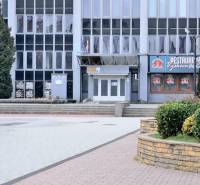 Kancelária s výhľadom na centrum Michaloviec. 16 m2 - Budova s kanceláriami na Námestí slobody v Michalovciach, obklopená zeleňou a chodníkmi.
