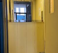 Kancelária s výhľadom na centrum Michaloviec. 16 m2 - Interiér kancelárií s výťahom a žltými stenami.