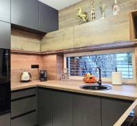 - KRÁTKODOBÝ PRENÁJOM - RODINNÝ DOM - 105 m2 - ROVINKA - Kuchyňa v rodinnom dome s tmavými skrinkami a podlahou s dreveným dekorom.