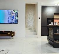 - KRÁTKODOBÝ PRENÁJOM - RODINNÝ DOM - 105 m2 - ROVINKA - Obývačka v rodinnom dome s krbom a kuchynským ostrovom, podlaha s dreveným dekorom.