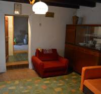 CHalúpka, na rekonštrukciu za cenu pozemku, dom Abrahám! - Obývacia izba v rodinnom dome s červeným kreslom a skrinkou s riadmi.