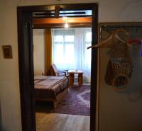 CHalúpka, na rekonštrukciu za cenu pozemku, dom Abrahám! - Interiér rodinného domu s posteľou a drevenou podlahou, cez dvere vidno izbu.